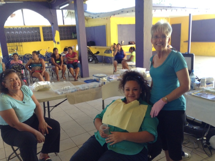 Jan English of Princeton, Illinois has returned to San Predro for at least her third time, performing extractions and fillings on residents. In the chair is Adayli Moncada of Caye Caulker while her mother-in-law Rosie Wejbe waits nearby.